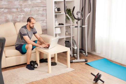 Man in sportswear at home searching online body training during global self isolation.