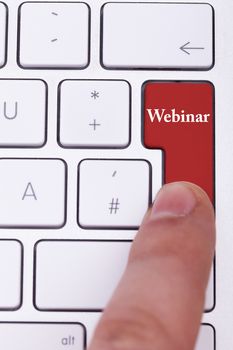 Finger pressing on red webinar button on metallic keyboard. Online learning