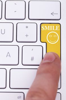 Finger pushing smile button on keyboard with a smile sign on it