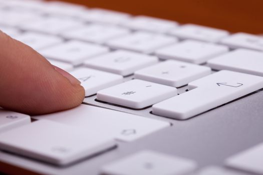 Finger pressing on keyboard key in close up