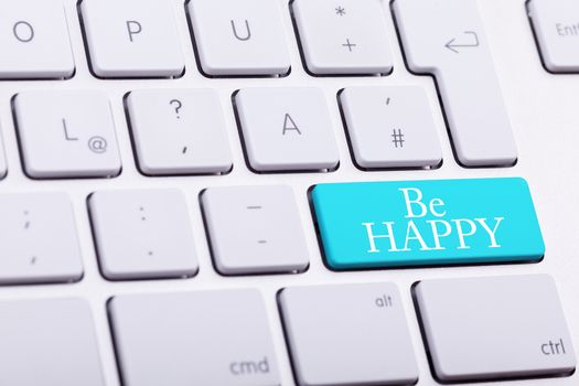 Elegant keyboard with BE HAPPY word in blue button close up photo
