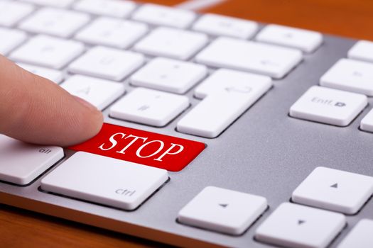 Finger pushing red stop button on modern keyboard. Danger and web content