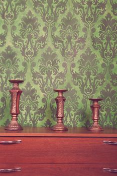 Three vintage chandeliers on green rococo style pattern background. Rich interior. Vintage toning