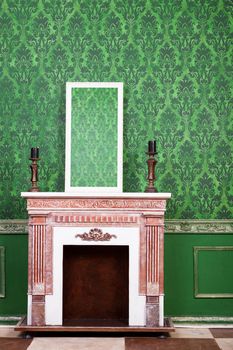 Old vintage mirrod in woden frame on chimney on green vintage pattern background