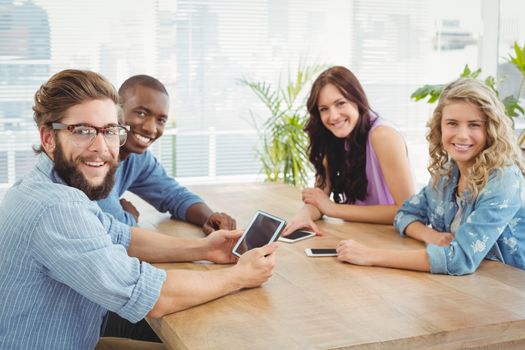 Portrait of smiling business professionals using technology at desk in office