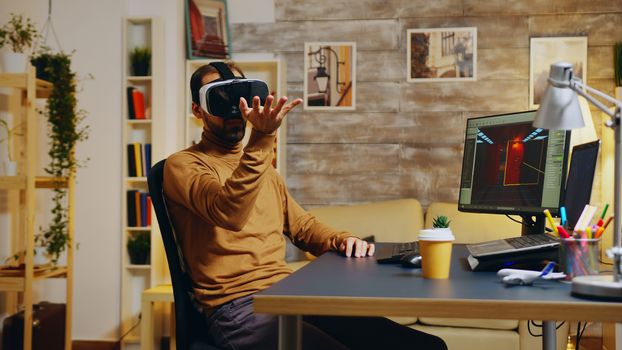 Game developer with virtual reality headset doing hand gesture while creating new graphics of the game.