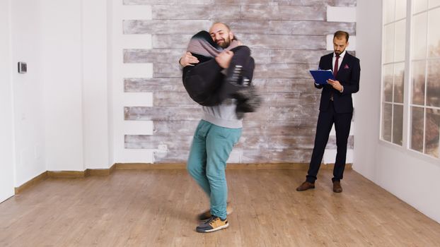 Boyfriend spining girlfriend after buying new apartment. Real estate agent signing documents in the background.