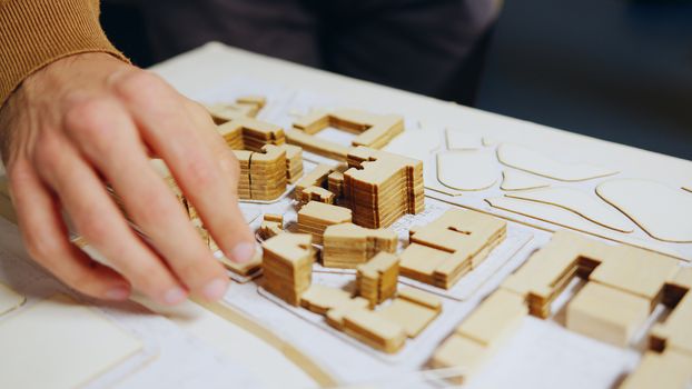 Close up of architect hand checking city model concept in his home office.
