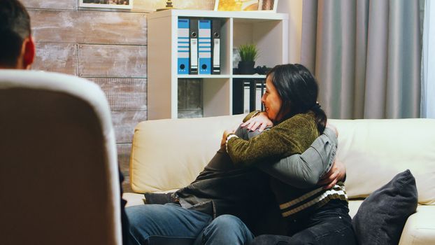 Husband and wife in couple therapy hug each other after talking about their difficulties in relationship.