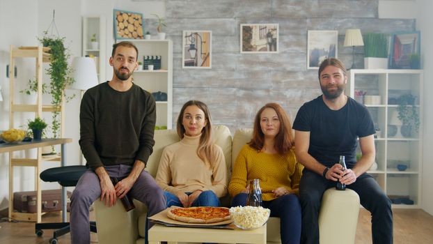 Group of friend enjoying a tasty pizza while socializing and watching sports on tv.