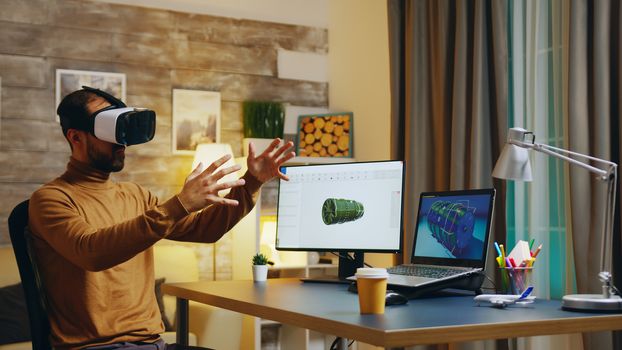 Engineer with virtual reality headset at his desk during night time working on a new technology for turbines.