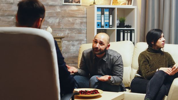 Angry boyfriend at couple therapy while girlfriend is crying. Relationship difficulties.