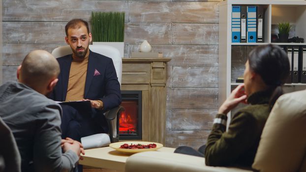 Bearded psychotherapist helping young couple with their relationship problem.