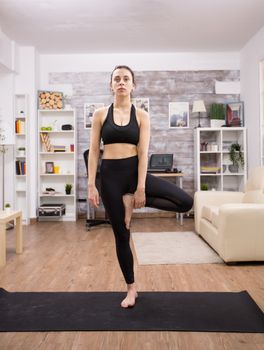 Caucasian woman standing in one leg focused on her good posture. Practicing yoga.