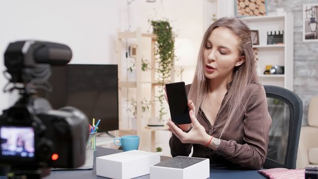 Social media star recording the unboxing of a new phone in front of the camera in her studio