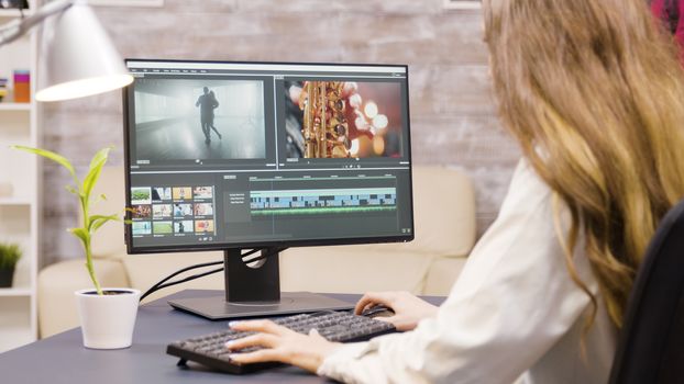 Creative female filmmaker working on post production of a movie from home. Boyfriend in the background.