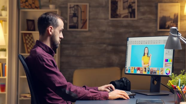 Male photographer using tablet to retouch photos on computer in home office. Artist working at night.