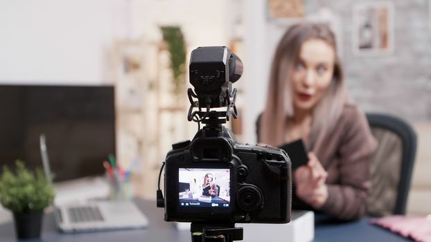 Female makeup artist recording unboxing of a new phone. Selective focus on the camera