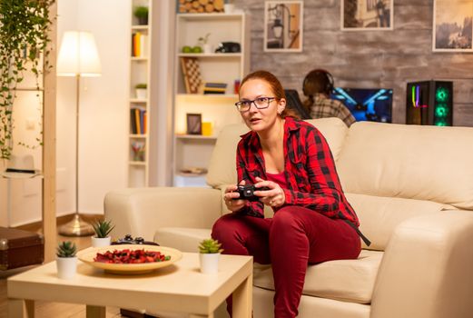 Woman gamer playing video games on the console in the living room late at night