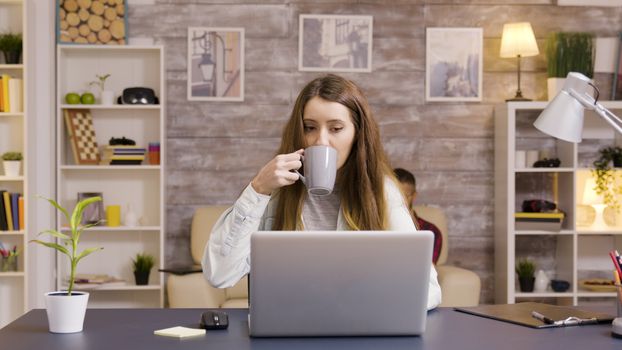 Beautiful young female working on laptop in home office. Young freelancer working from home.