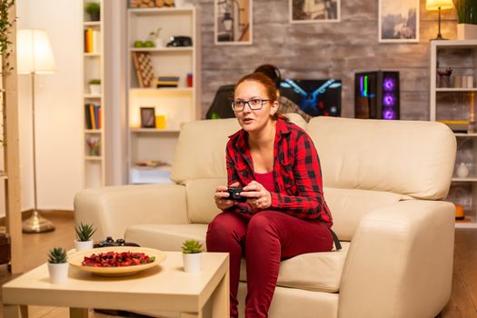 Woman gamer playing video games on the console in the living room late at night