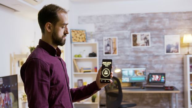 Man using a smart lights application to turn on the light bulbs in the house.