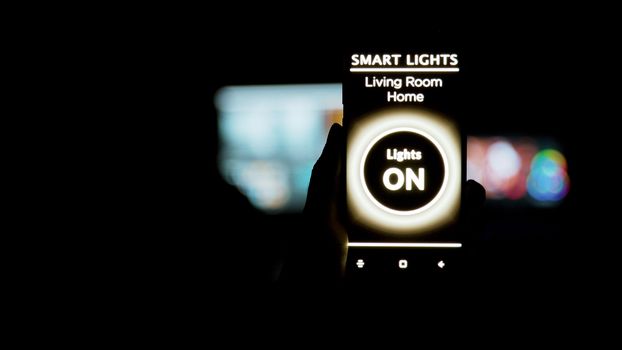 Close up shot of man holding a smartphone in hands with a smart light application on it