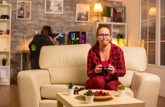 Woman gamer playing video games on the console in the living room late at night
