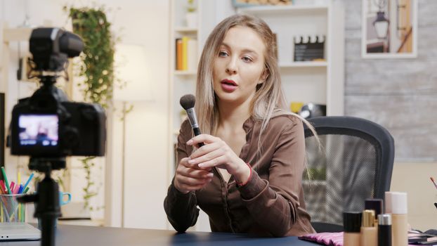 Young beautiful beauty vlogger recording makeup tutorial for subscribers. She uses professional filming equipment