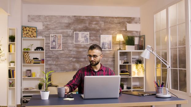 Handsome caucasian freelancer working on laptop from home office.