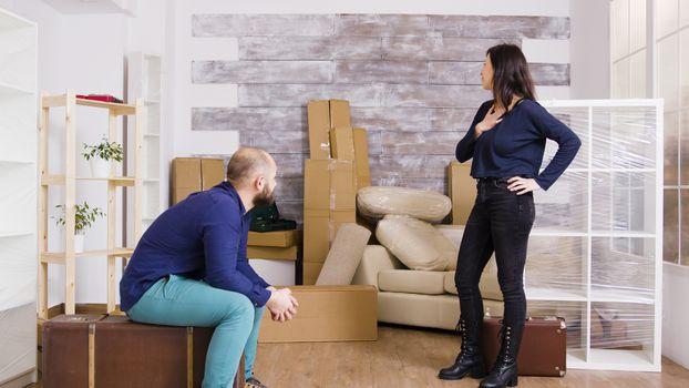 Young couple arriving with suitcases in their new apartment. Cardboard boxes in the background.