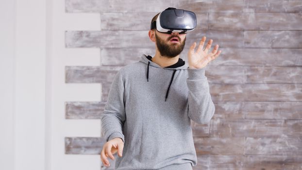 Caucasian home designer using virtual reality goggles inside of an empty apartment to decorate it in cyberspace