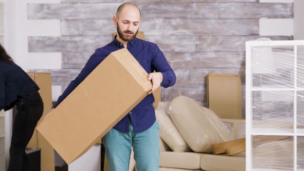 Caucasian young couple moving in their new home. Professional movers delivering cardboard boxes to door.