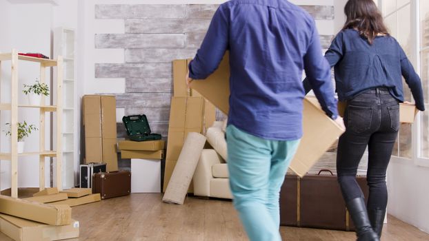 Young couple carrying boxes in their new apartment. Moving day for flat owners.