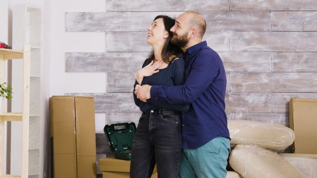 Happy young couple hugging each other in their new apartment. Cardboard boxes in the background.