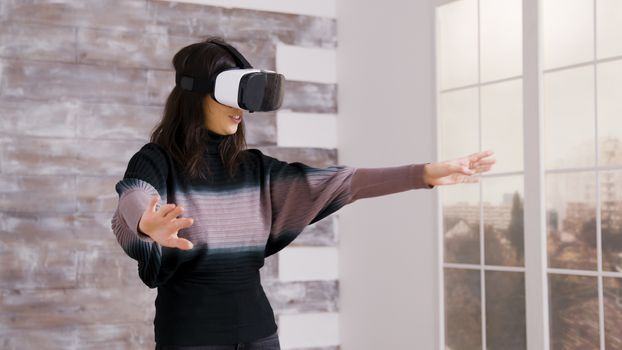 Beautiful female home designer using virtual reality goggles inside of an empty apartment.