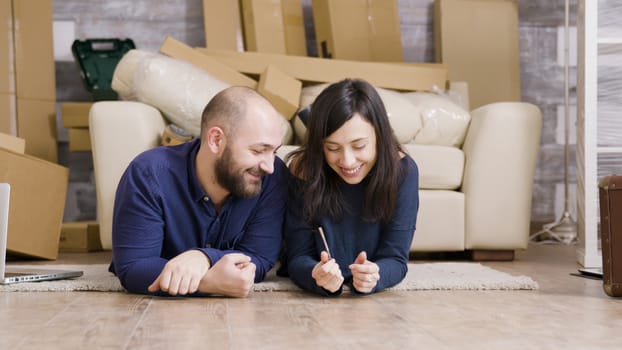 Couple laying down on the floor of their new apartment. Boyfriend giving keys to his girlfriend.