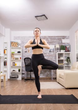 Brunette woman smiling while doing yoga pose standing in one leg.