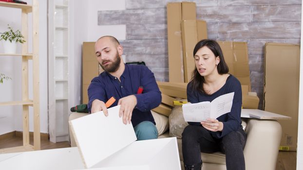 Couple assembling furniture using instructions in their new apartment. Couple working as a team.