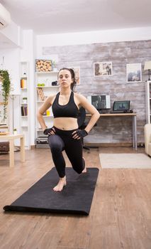 Front view of woman with healthy lifestyle doing lunges exercise at home.