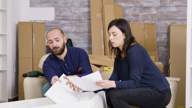 Couple reads instructions for assembly of furniture in new house. After job is done they do high five.