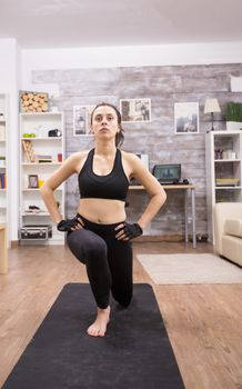 Athletic woman doing lunges workout for legs at home.