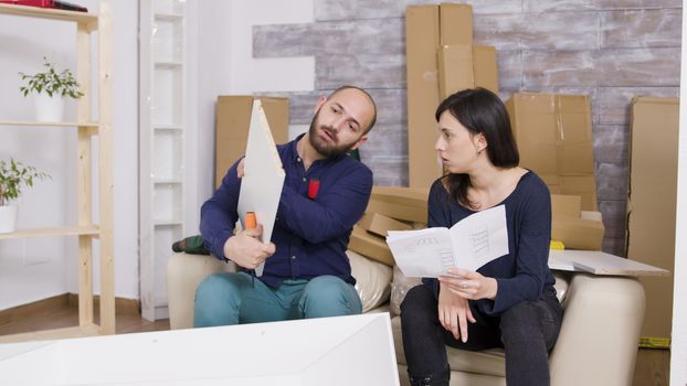 Couple assembling furniture using instructions in their new apartment. Couple working as a team.