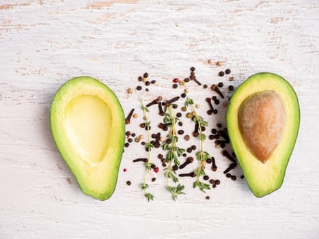 Avocado cut in half on white wooden board.