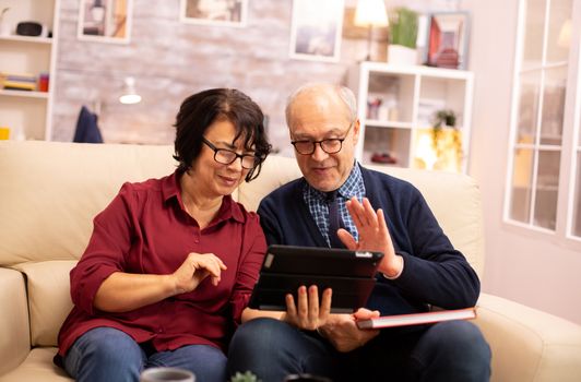 Beautiful old couple using a digital tablet to chat with their family. Elderly people using modern technology