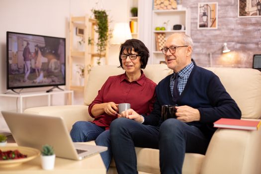 Elderly old couple using modern laptop to chat with their grandson. Grandmother and grandfather using modern technology