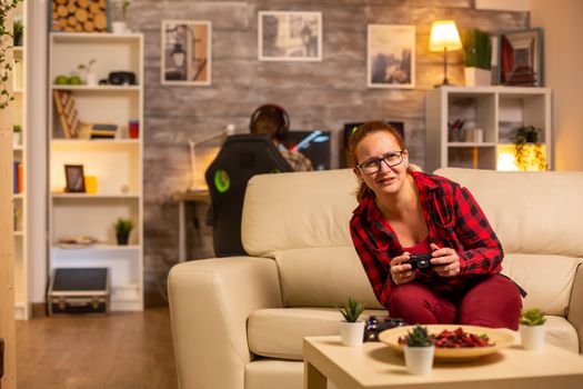 Woman gamer playing video games on the console in the living room late at night