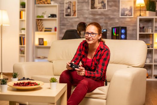 Woman gamer playing video games on the console in the living room late at night