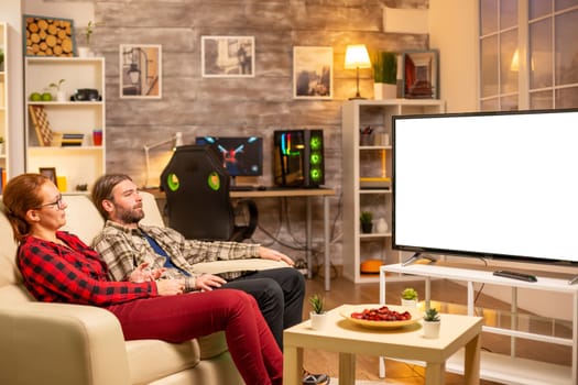 Couple looking at white isolated TV screen late at night in living room.