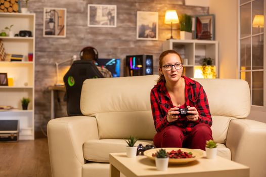 Woman gamer playing video games on the console in the living room late at night